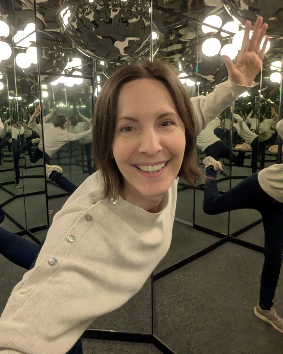 Malin Österlöf smiling and waving in a room full of mirrors